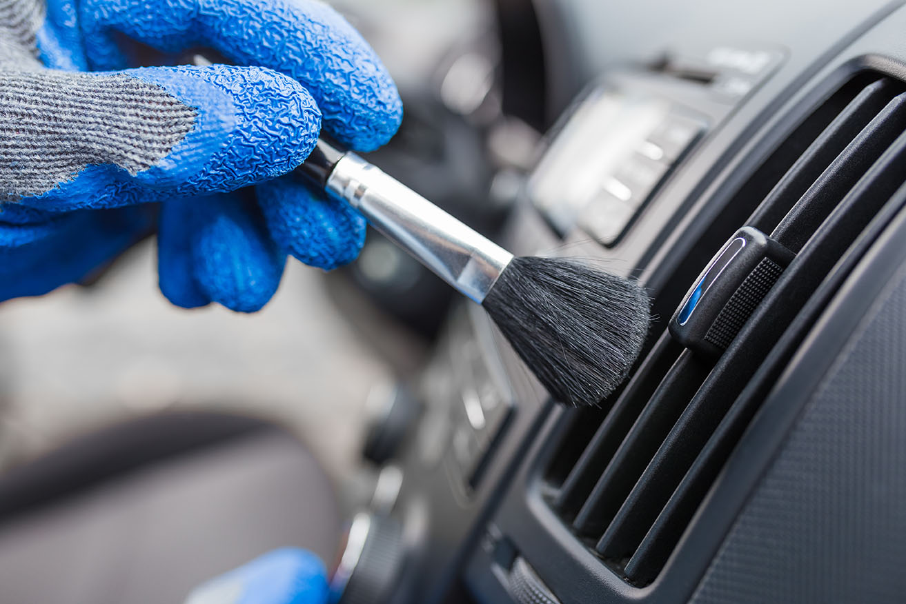 Car detailer brushing the AC vents in a car Car detailer brushing the AC vents in a car