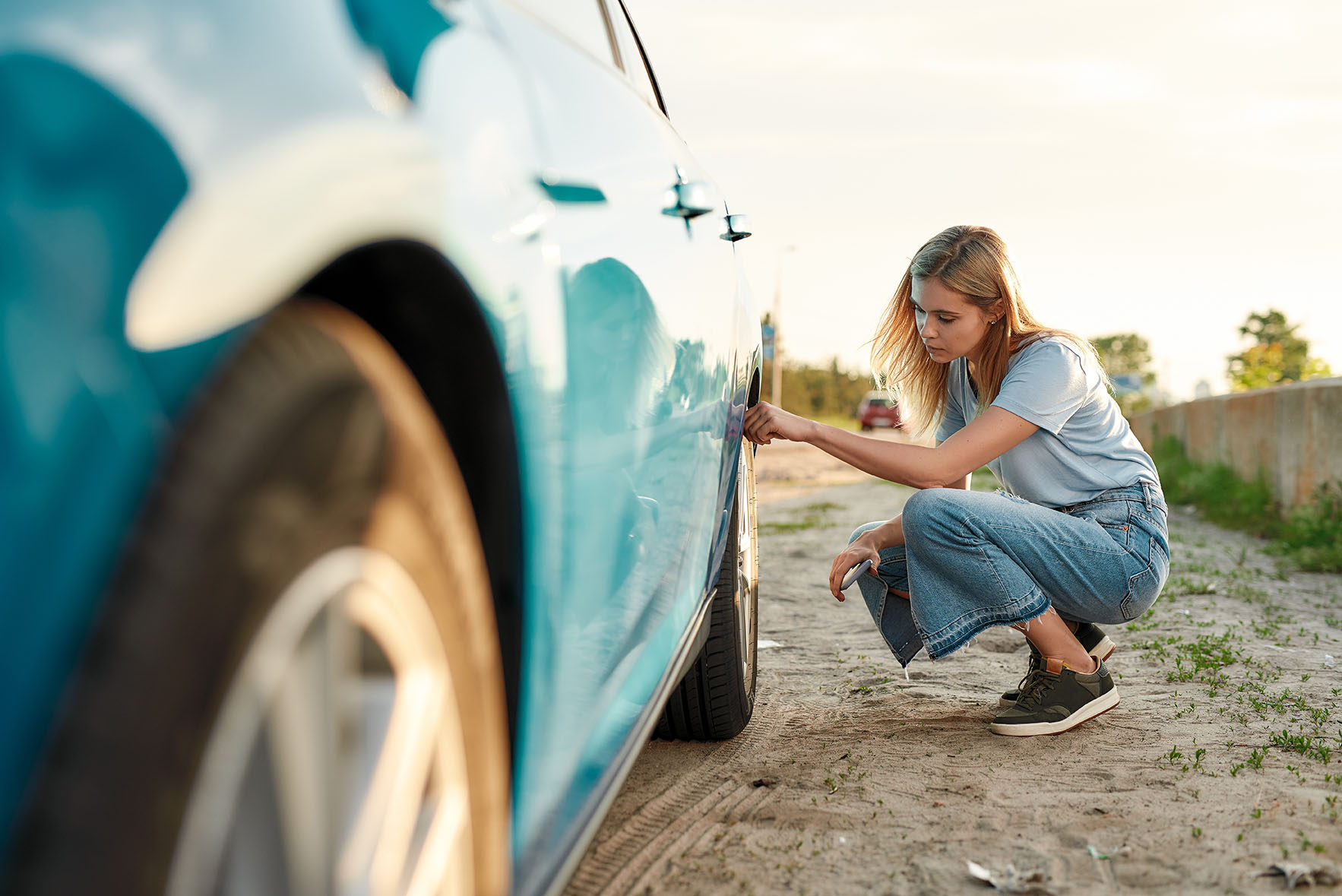 Woman checking the tire pressure on her car Woman checking the tire pressure on her car